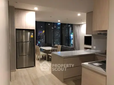 Modern open-plan kitchen and living area with city view, featuring sleek cabinetry and dining set.