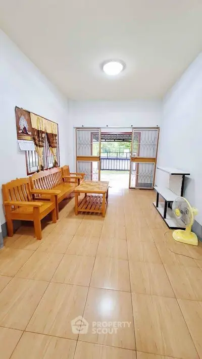 Spacious living room with wooden furniture and large windows for natural light.
