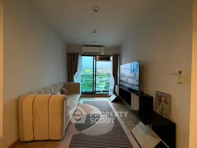 Modern living room with stylish sofa and large TV, featuring a balcony with city view.