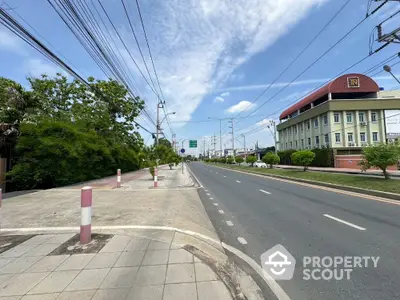 Scenic road view with lush greenery and modern building, ideal for urban development.