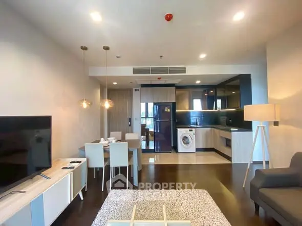 Modern open-plan living room with kitchen and dining area, featuring stylish furniture and appliances.