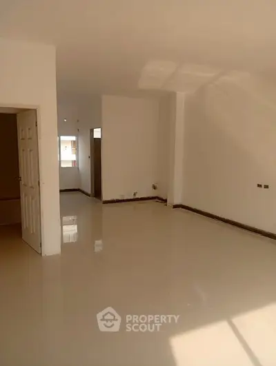 Spacious unfurnished living room with glossy floors and ample natural light.