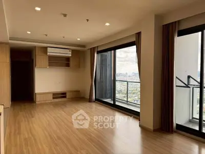 Spacious modern living room with large windows and city view, featuring sleek wooden flooring and built-in storage.