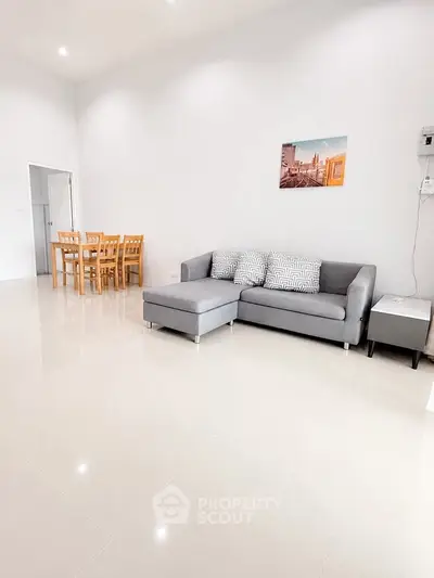 Spacious living room with modern gray sofa and dining area, perfect for family gatherings.