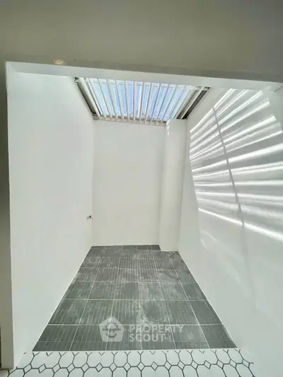 Modern minimalist space with skylight and tiled floor, perfect for creative design possibilities.