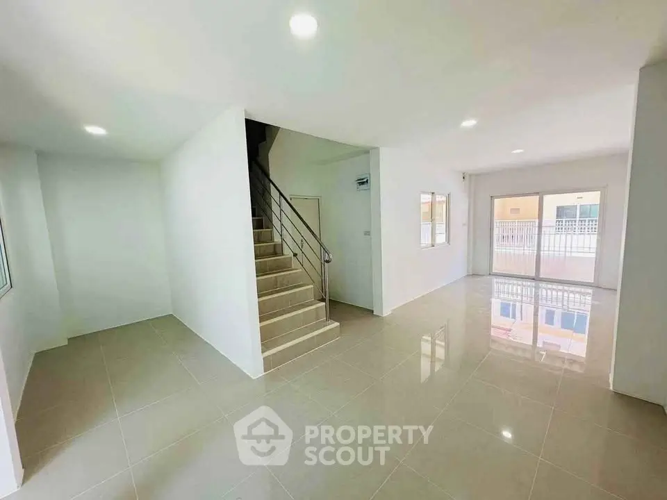 Spacious modern living room with glossy tiled floors and staircase