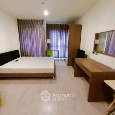 Spacious bedroom with modern furnishings and large window for natural light.