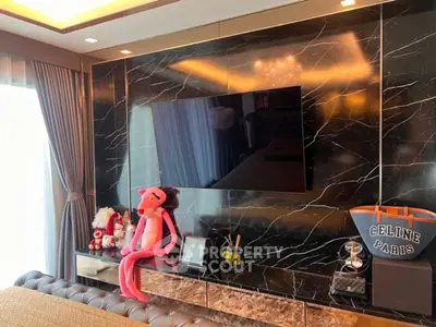 Luxurious living room with marble wall and mounted TV, featuring elegant decor and plush seating.