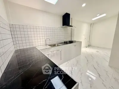 Modern kitchen with sleek black countertops and white tiled backsplash in a spacious open layout.