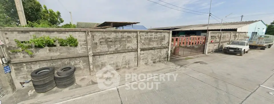 Industrial property with concrete walls and parking space, ideal for storage or workshop use.