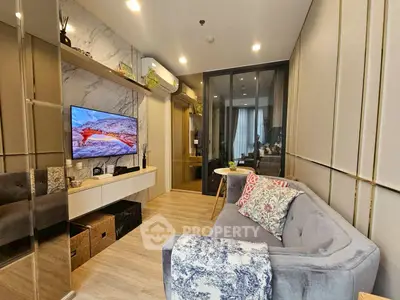 Modern living room with stylish decor and cozy seating area, featuring a wall-mounted TV and elegant shelving.