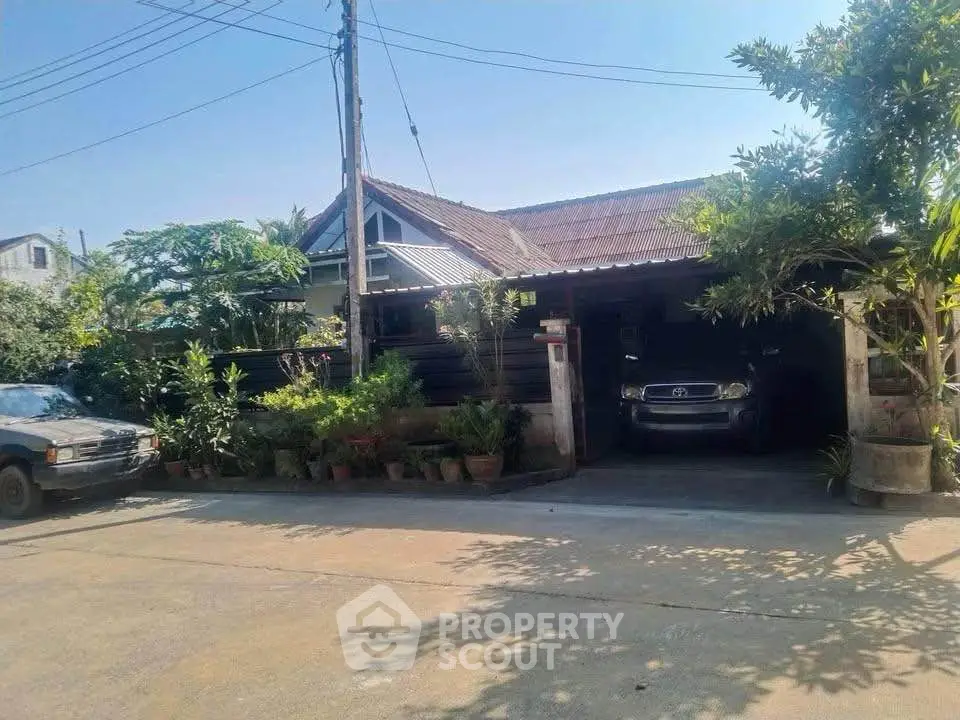 Charming single-story house with lush greenery and carport in a serene neighborhood.