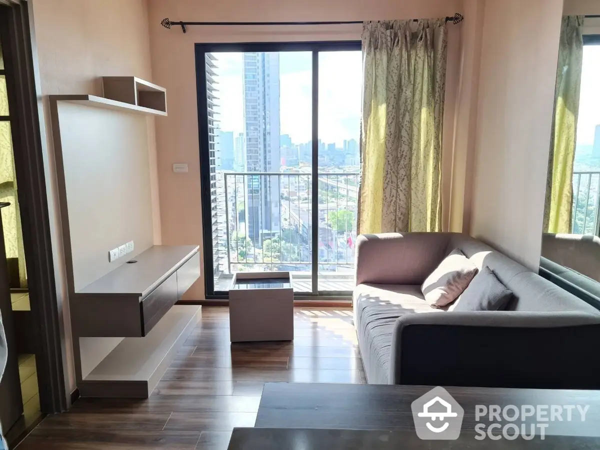 Spacious living room with modern furnishings, large windows, and access to a sunny balcony with a city view, perfect for urban living.