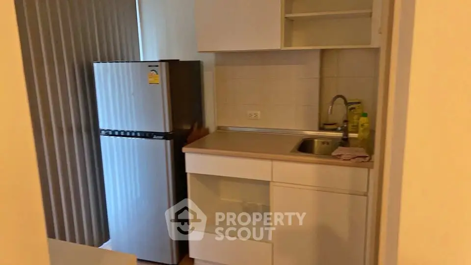 Compact kitchen with fridge and sink in modern apartment