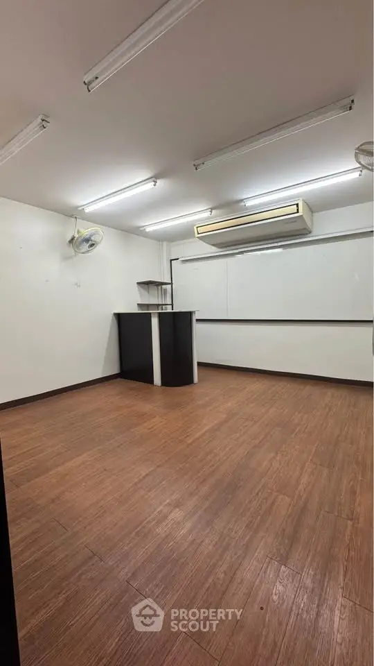 Spacious study room with wooden flooring and modern lighting.