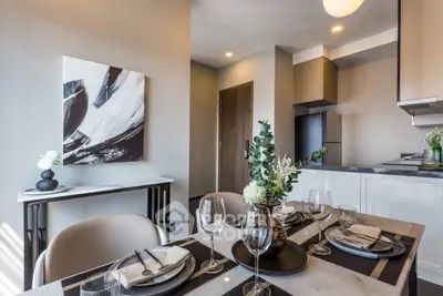 Modern dining area with elegant table setting and contemporary kitchen in open layout apartment.