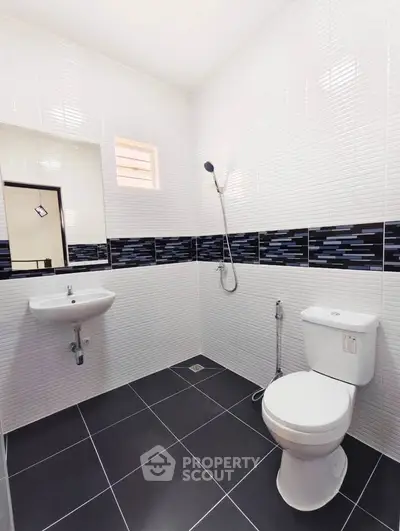 Modern bathroom with sleek black and white tiles and contemporary fixtures.