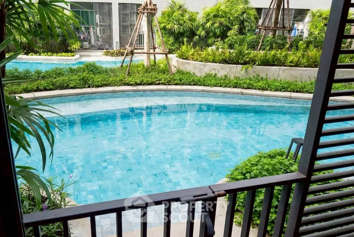 Luxurious poolside view with lush greenery in modern residential complex.