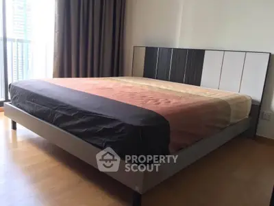 Spacious bedroom with modern bed and large window offering natural light.