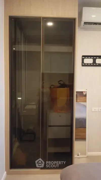 Modern bedroom with sleek glass wardrobe and air conditioning unit