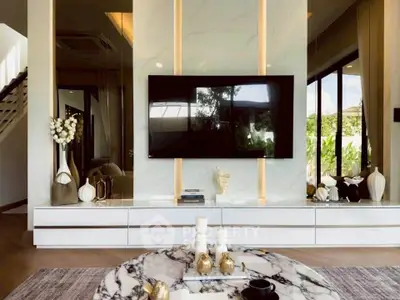 Luxurious living room with modern decor and large TV, featuring elegant marble accents and stylish furnishings.