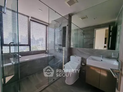 Luxurious modern bathroom with glass shower and bathtub, featuring sleek design and ample natural light.