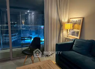 Stylish living room with modern furniture and city view from balcony at night.