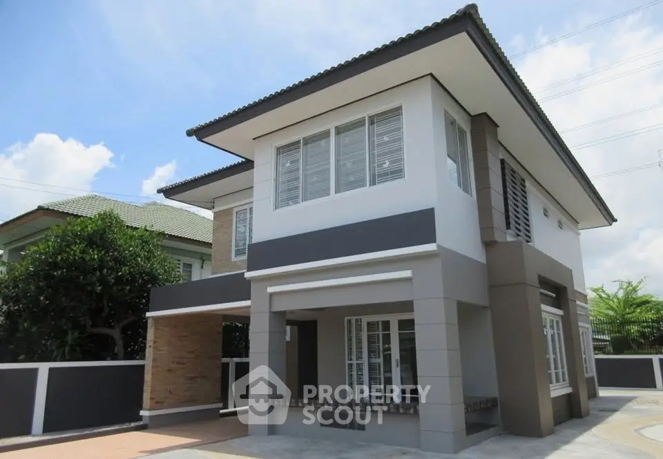 Modern two-story house with sleek design and spacious driveway under clear blue sky.