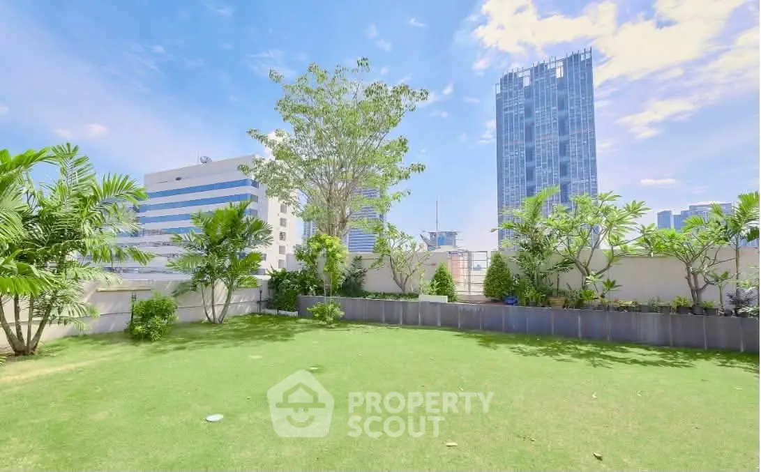 Spacious urban garden with lush greenery and city skyline views, perfect for relaxation and outdoor activities.