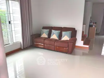 Spacious living room with modern brown sofa and large window for natural light.