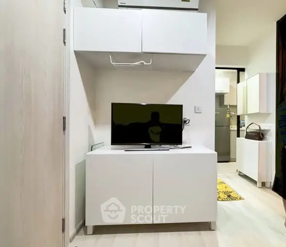 Modern living room with sleek white cabinetry and flat-screen TV, showcasing minimalist design and functionality.