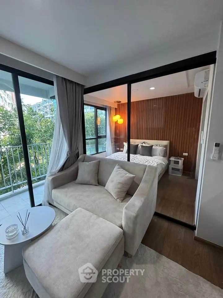 Modern apartment with cozy living room and bedroom, featuring large windows and a balcony view.