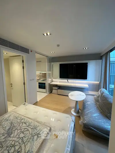 Modern studio apartment with stylish decor, featuring a cozy living area and a sleek wall-mounted TV.