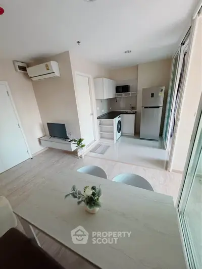 Modern open-plan living room with kitchen, featuring sleek appliances and stylish decor.