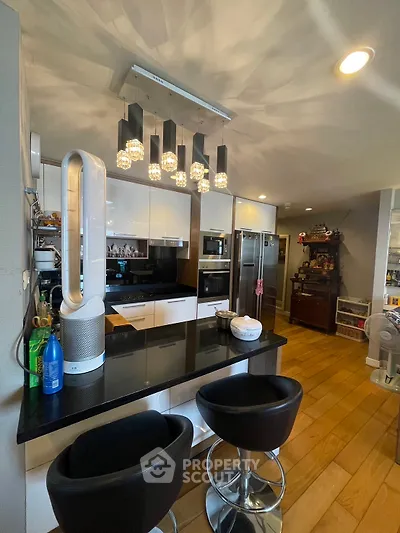 Modern kitchen with sleek design, featuring bar seating and contemporary lighting.