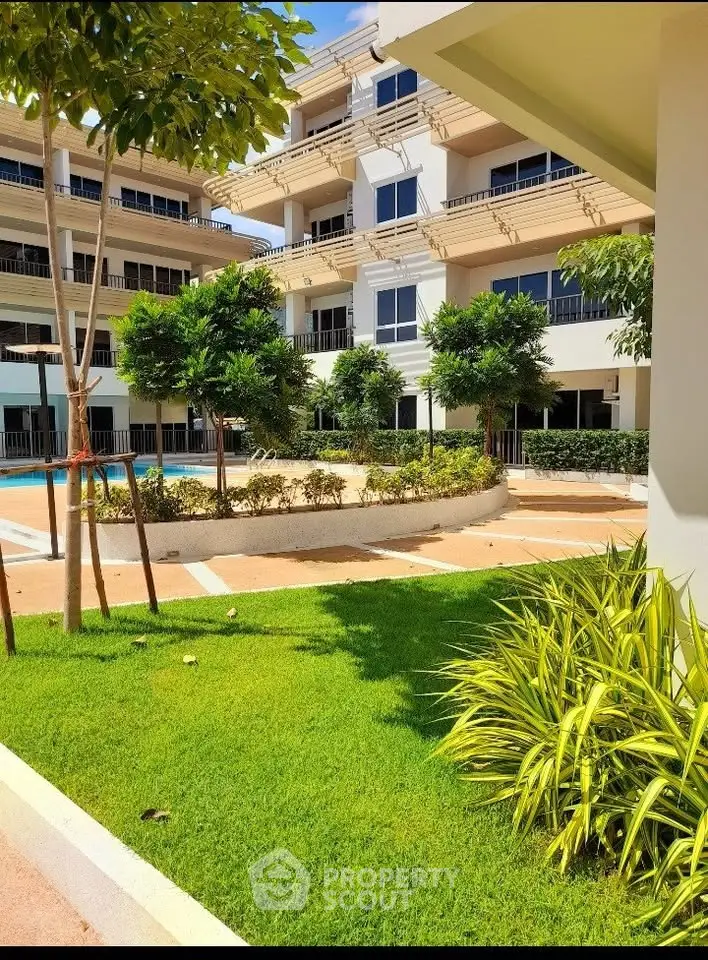 Luxurious apartment complex with lush garden and pool view