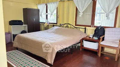 Cozy bedroom with wooden floors and large windows in a charming home.