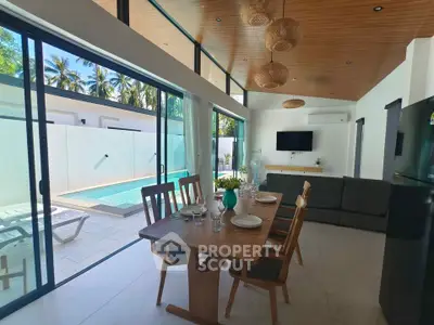 Luxurious open-plan living room with pool view, modern dining set, and stylish decor in a tropical setting.