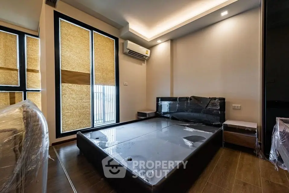 Modern bedroom with sleek design and large windows, featuring a stylish bed and air conditioning.
