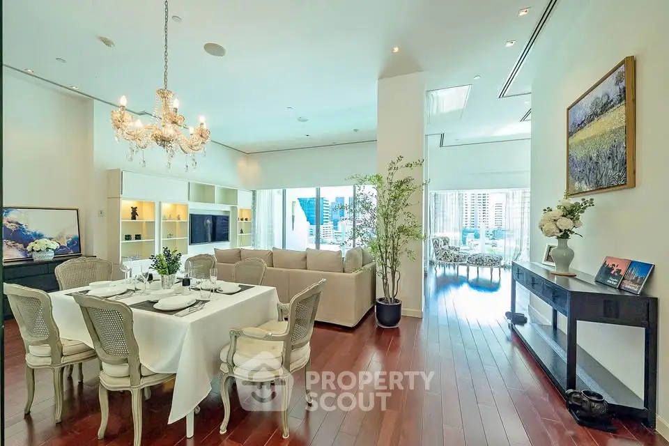 Luxurious open-plan living and dining area with elegant chandelier and city view.