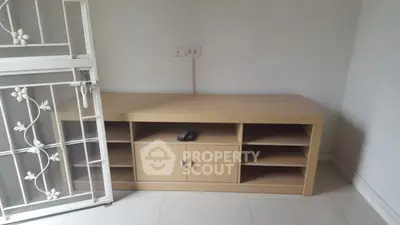 Minimalist wooden TV stand in a bright room with tiled floor and decorative door.