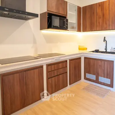 Modern kitchen with wooden cabinets and sleek appliances in a contemporary apartment.