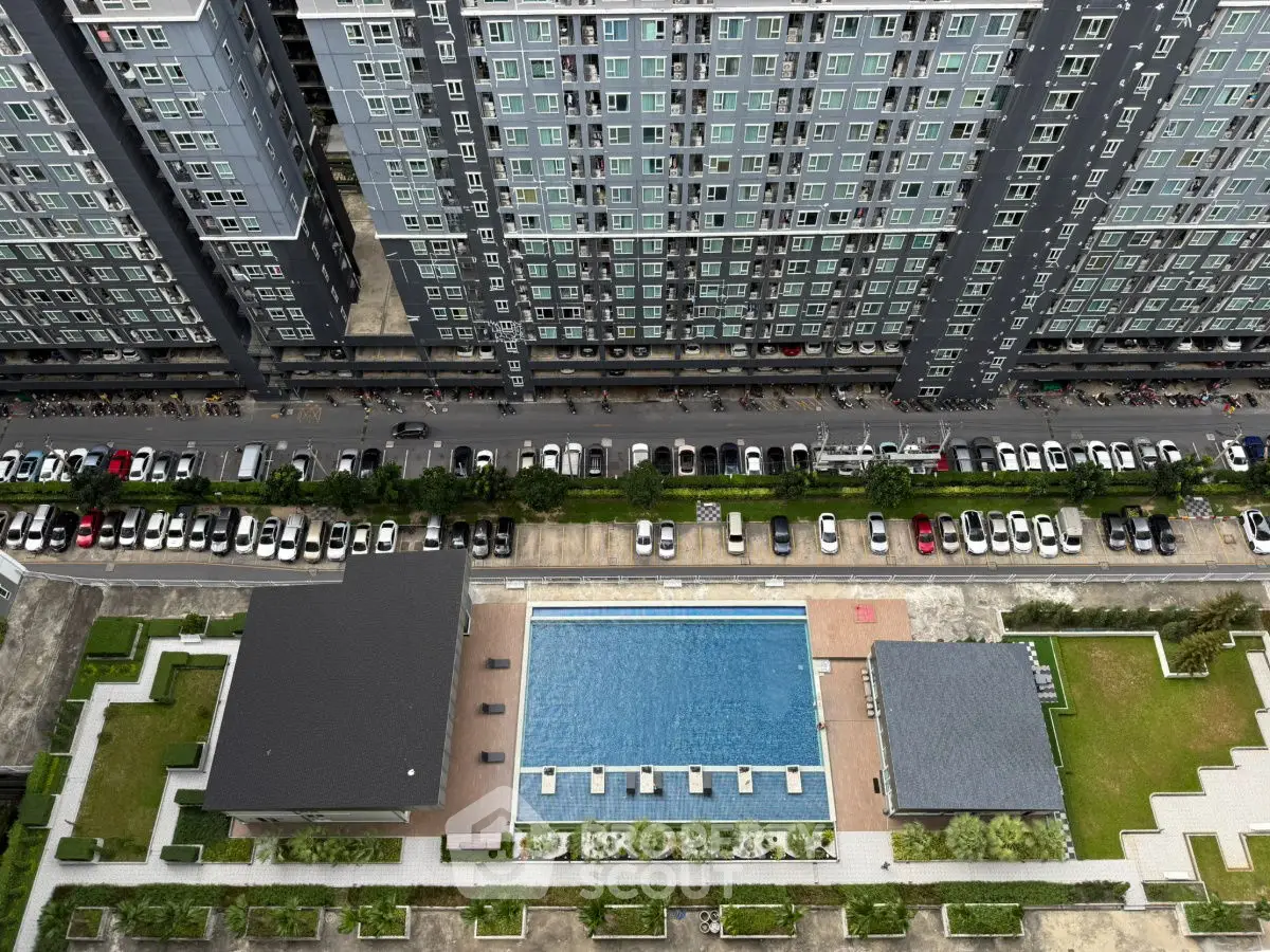 Aerial view of modern apartment complex with swimming pool and parking area.