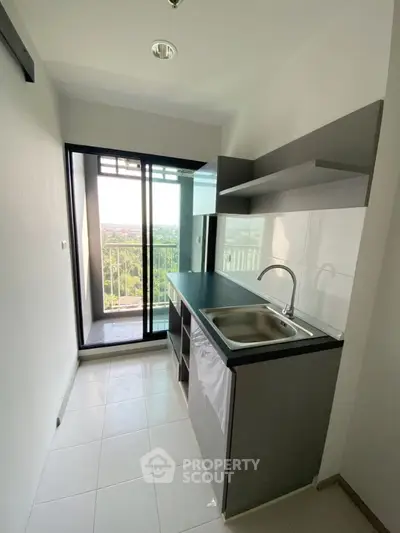 Modern compact kitchen with balcony view in high-rise apartment