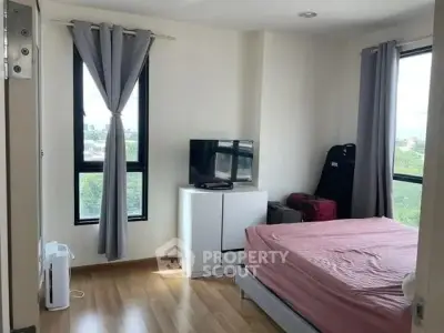 Cozy bedroom with large windows and natural light, featuring a TV and modern furnishings.