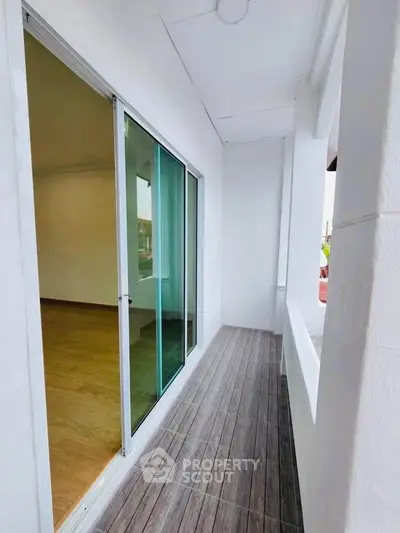 Charming narrow balcony with sliding glass doors and wood-like tile flooring.
