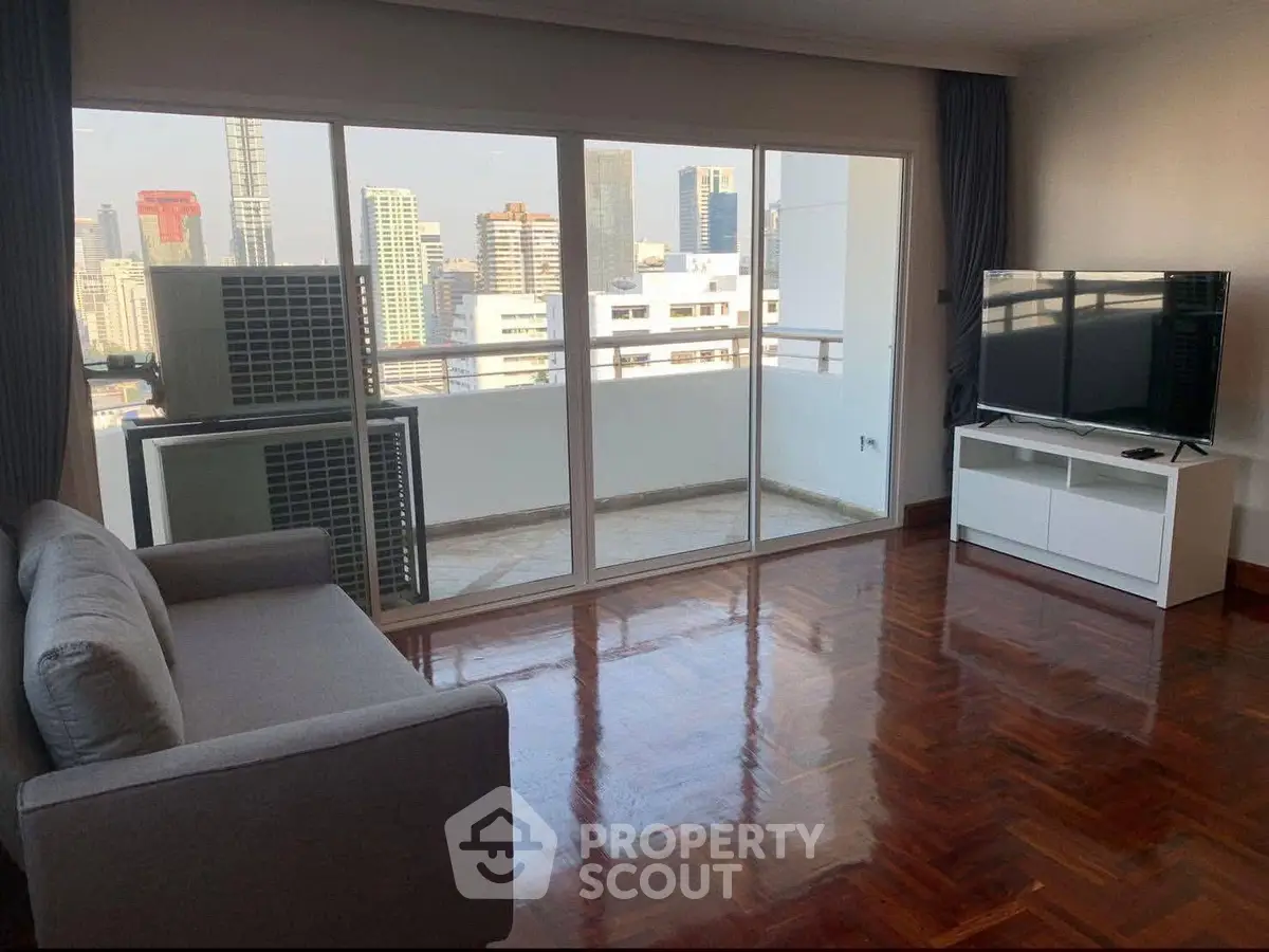 Spacious living room with city view and modern furnishings in a high-rise apartment.