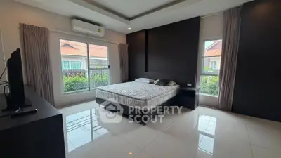 Spacious bedroom with large windows and modern decor in a stylish home.