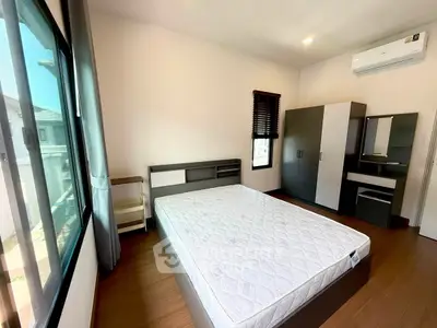 Modern bedroom with large window, stylish furniture, and air conditioning unit.