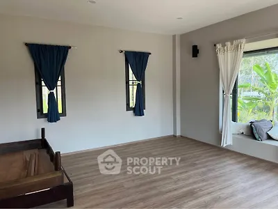 Spacious bedroom with large windows and wooden flooring